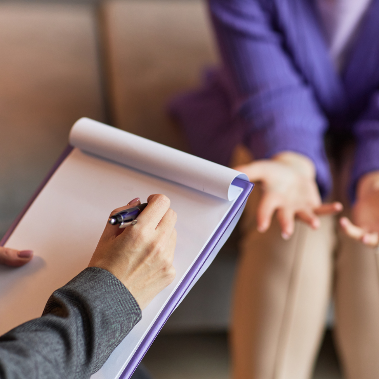 A therapist writes down notes while in a session with a patient.