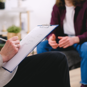 A therapist writes down notes during a session with a patient.