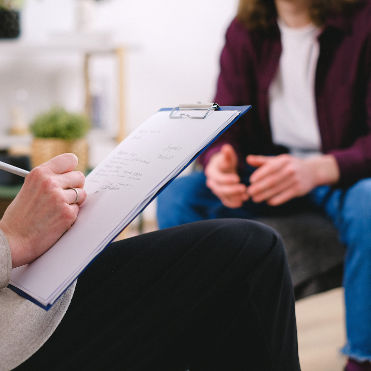 A therapist writes down notes during a session with a patient.